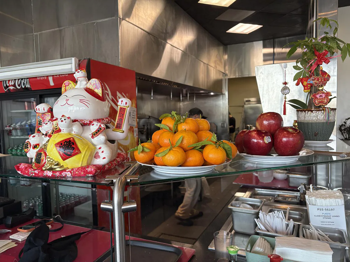 Maneki neko figurine with oranges and apples at restaurant counter at Tasty Sushi, a Japanese Restaurant in Sacramento
